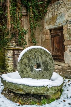 Old grinding wheel covered with snow in the winter