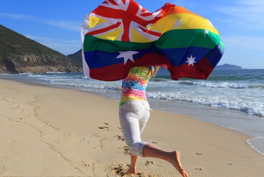Woman running along the beach with a rainbow Australian flag.  On November 15, 2017, Ausralians voted yes to marriage equality allowing for laws to be changed