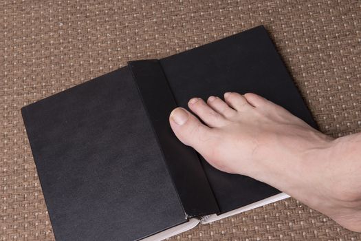 a book on the carpet with a barefoot foot above