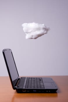 a laptop on the table with the cloud above