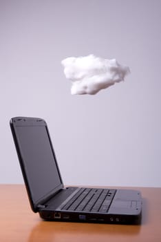 a laptop on the table with the cloud above