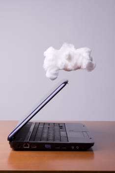 a laptop on the table with the cloud above