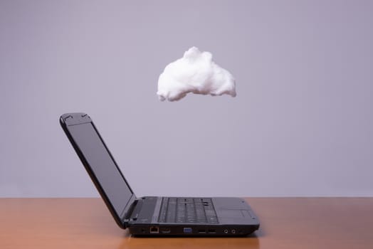 a laptop on the table with the cloud above