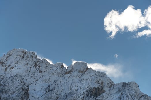 a cloud over a snowy mountain