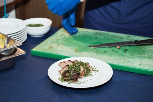 Young white chef in kitchen interior. Man marinating beef steak on a tray. Meat ready for the grill and serve. Only hands.