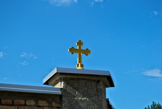Cross on monastery fence and sky in background