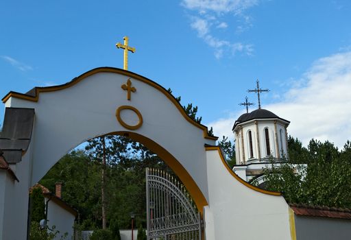 Entrance to a monastery and church tower in background
