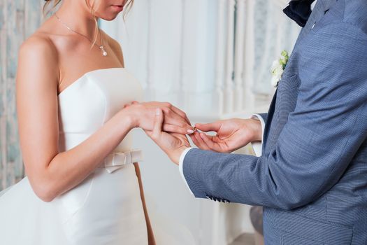 Wedding day. The groom places the ring on the bride's hand.