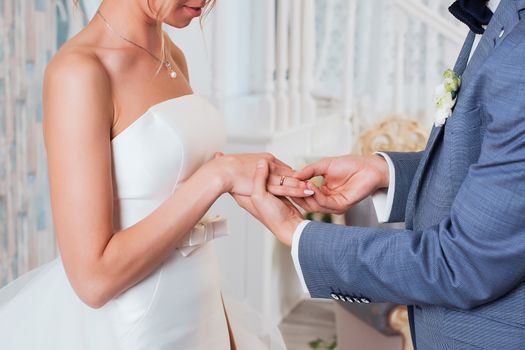 Wedding day. The groom places the ring on the bride's hand.