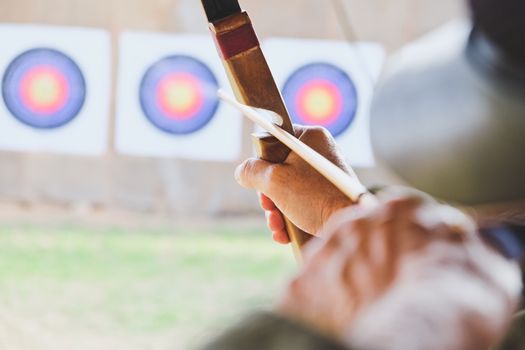 Archer holds his bow aiming at a target