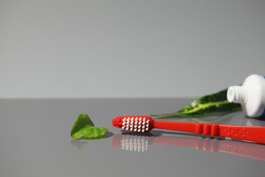 Toothbrush tube of toothpaste with green leaves, conceptual image, promoting healthy living. Copy space.