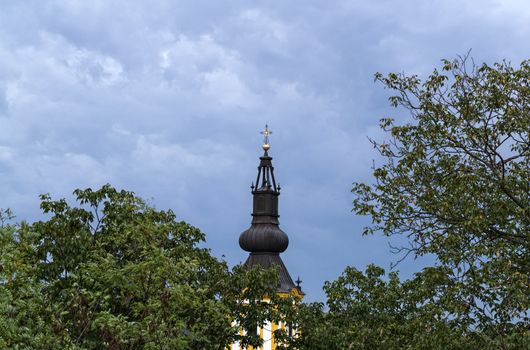 Top of the church between trees and sky from far