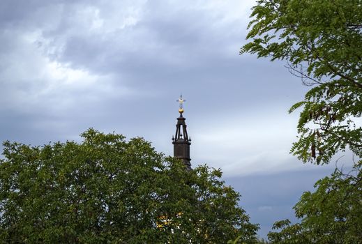 Top of the church between trees and sky from far