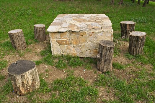 Stone table and wooden log as chairs in park