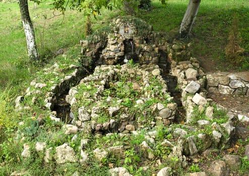 Small fountain in park, surrounded by trees