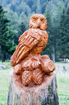 Sculpture of an owl on a tree trunk in a park in the dolomites in Italy