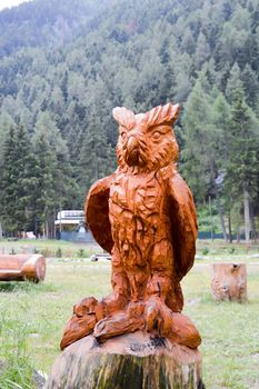 Sculpture of an owl on a tree trunk in a park in the dolomites in Italy