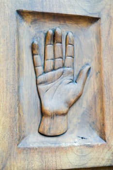 Reproduction of a hand acting as a pusher on a wooden door in the dolomites in Italy