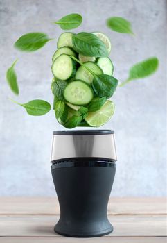 Fresh green fruits and vegetables spinning around a blender 