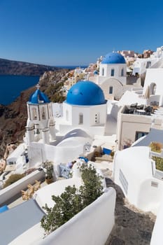 Cityscape of Oia, traditional greek village with blue domes of churches, Santorini island, Greece.