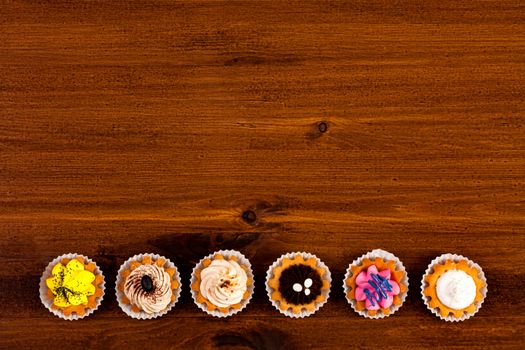 Cupcakes on a brown wooden table, top view