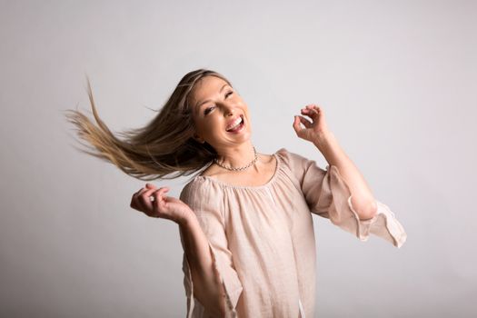 Smiling vivacious carefree woman flicking long blonde hair