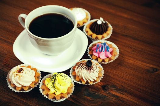 Closeup shot of small cup of coffee with colorful cupcakes