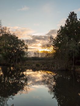 beautiful sun set autumn light sky over river trees reflections water surface; essex; england; uk