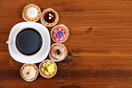 Closeup shot of small cup of coffee with colorful cupcakes