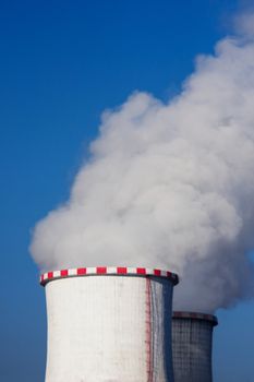 A very large column of white steam coming from a couple of furnaces in a power plant chilling station