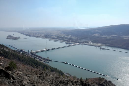 A very big hydroelectric power plant situated on a big river with bridge and sluice gates