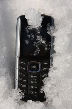 An old rugged GSM phone covered with ice 