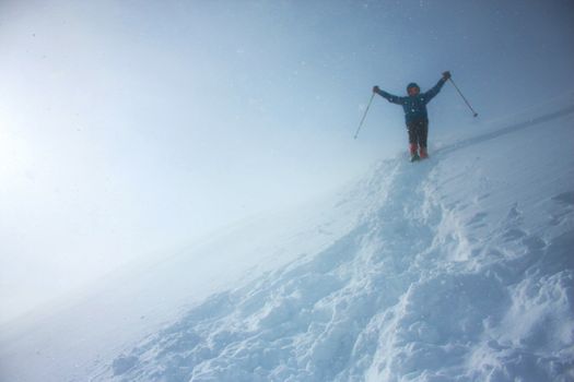 A mountaineer descending the slope with a salute raising both hands