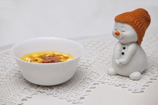 Ice cream cup with jam snowman figurine in a knitted cap close-up