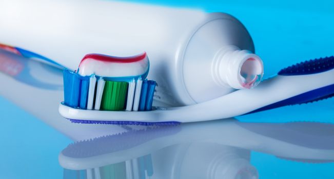 toothbrush with paste on a blue background with reflection