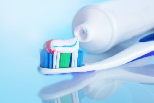 toothbrush with paste on a blue background with reflection