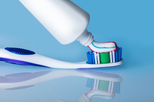 toothbrush with paste on a blue background with reflection