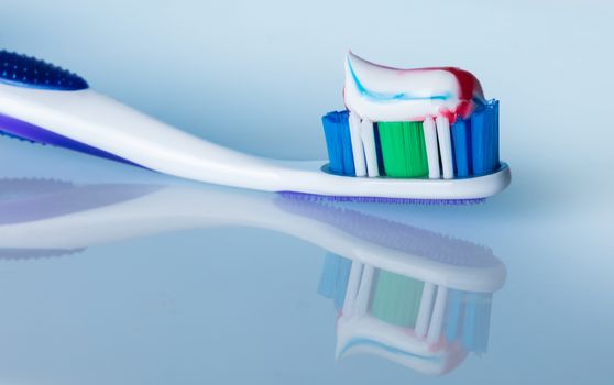 toothbrush with paste on a blue background with reflection