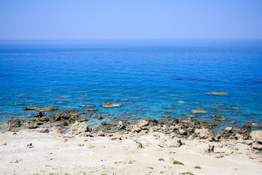 Rocky beach with beautiful view of the deep blue sea and clear sky above horizon