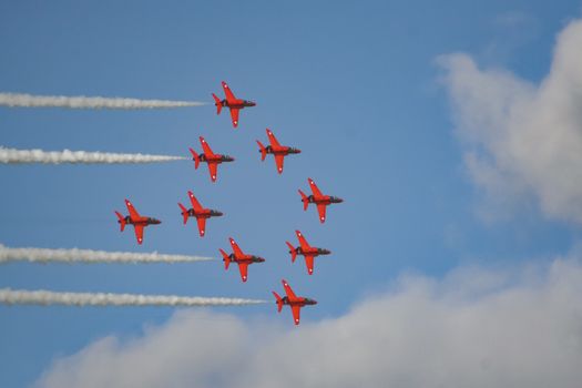 The royal air force red arrows air show flying in formation overhead in England.