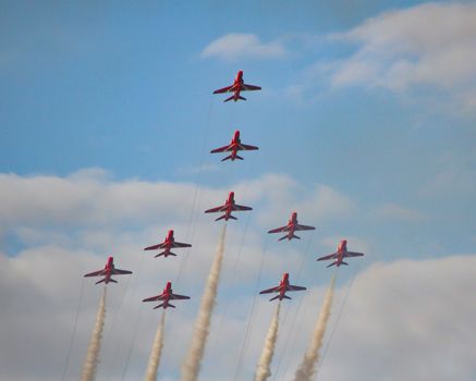 The royal air force red arrows air display flying in formation overhead in England.