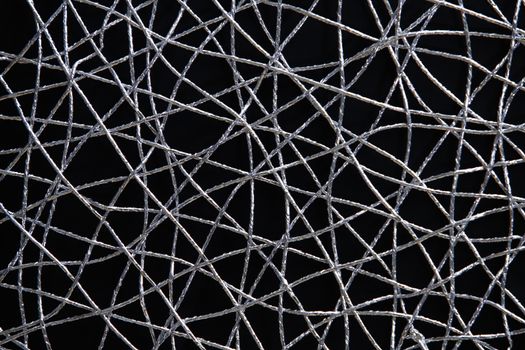 Chaotic weave of silver threads on black, abstract background