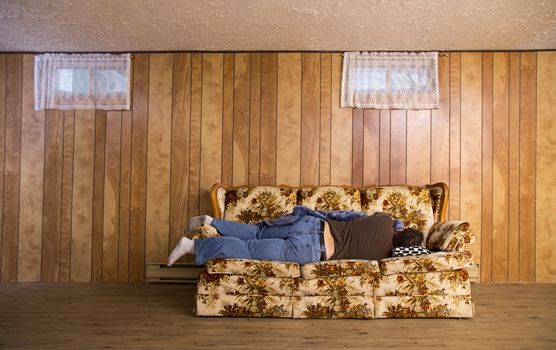 man sleeping on his side, on an old basement couch