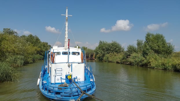 Old small tug boat towing a load with visible hawser in tension