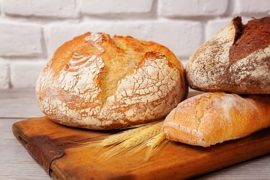 Crannied rustical homemade bread on old cutting board. Different types of bread.