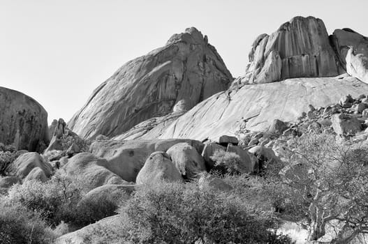 Spitzkoppe with sandstone boulders in the foreground, Namibia. Monochrome
