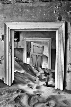 Sand taking over an historic old building at the ghost town of Kolmanskop near Luderitz, Namibia. Monochrome
