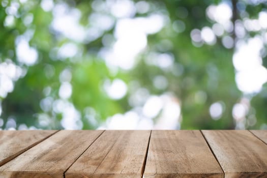 Wood desk on nature green bokeh for a present product.