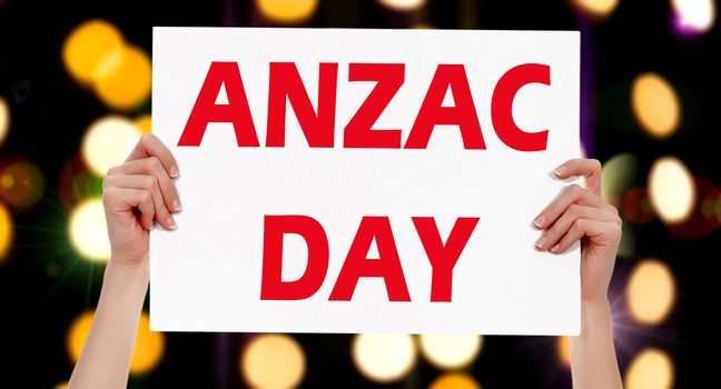 Anzac Day. Female hands holding a placard with abstract lights bokeh background