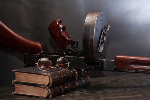 Old USA submachine gun closeup with books and spectacles